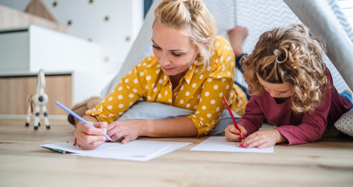A cute small girl with mother indoors at home, drawing pictures