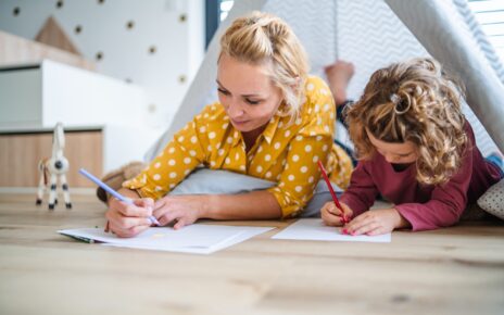 A cute small girl with mother indoors at home, drawing pictures