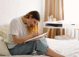 A teenage girl is drawing or doing homework in the bedroom. A teenager studies at home.
