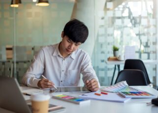 Asian man designer is drawing, creating a sample design using a color sample tablet at the office.