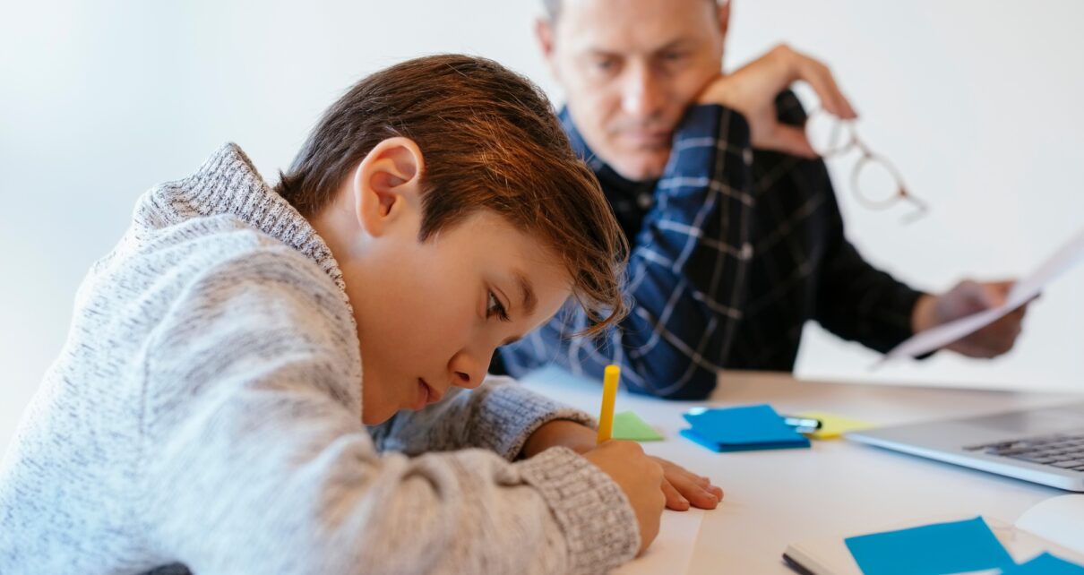 Businessman at desk in office looking at son drawing