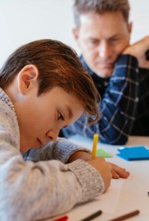 Businessman at desk in office looking at son drawing
