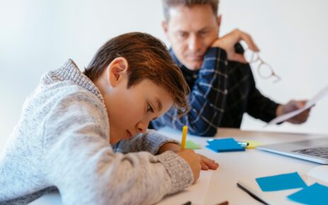 Businessman at desk in office looking at son drawing