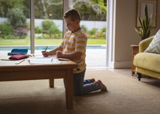 Caucasian boy drawing in his book sitting in the living room at home