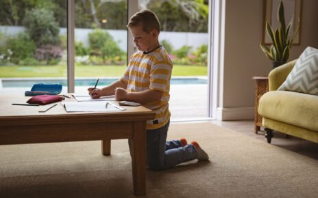 Caucasian boy drawing in his book sitting in the living room at home