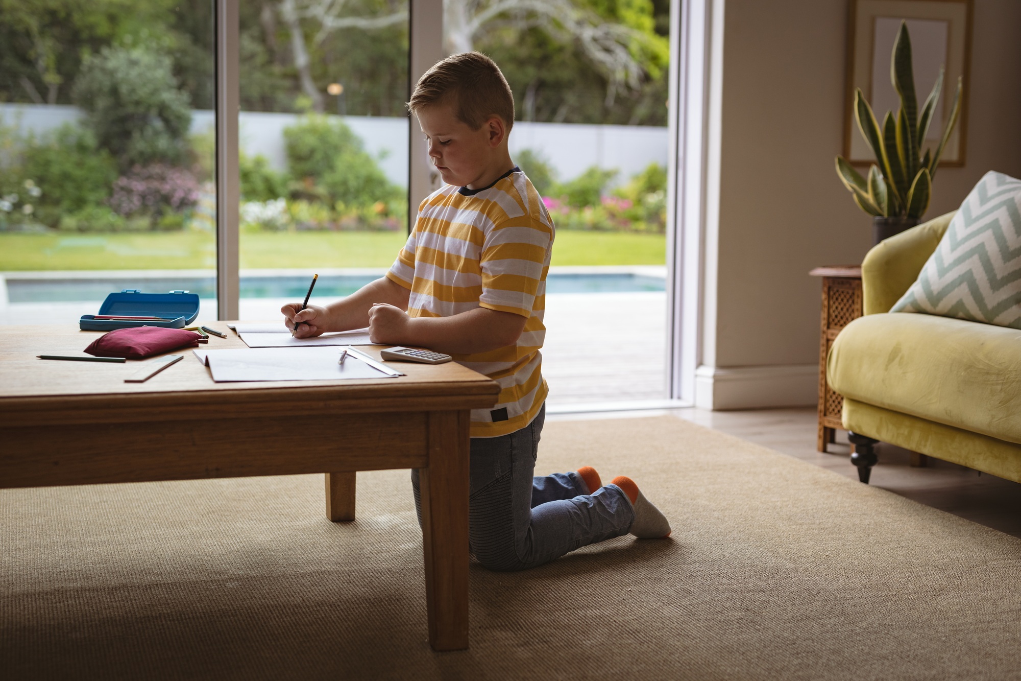 Caucasian boy drawing in his book sitting in the living room at home