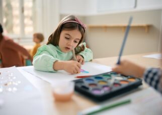 Creative girl drawing on the paper on art class at preschool.