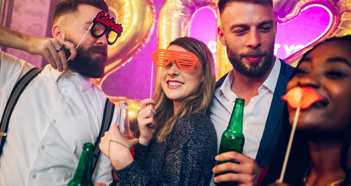 Multiracial friends celebrating new years eve with party props and drinks in the club