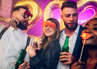 Multiracial friends celebrating new years eve with party props and drinks in the club