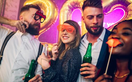 Multiracial friends celebrating new years eve with party props and drinks in the club