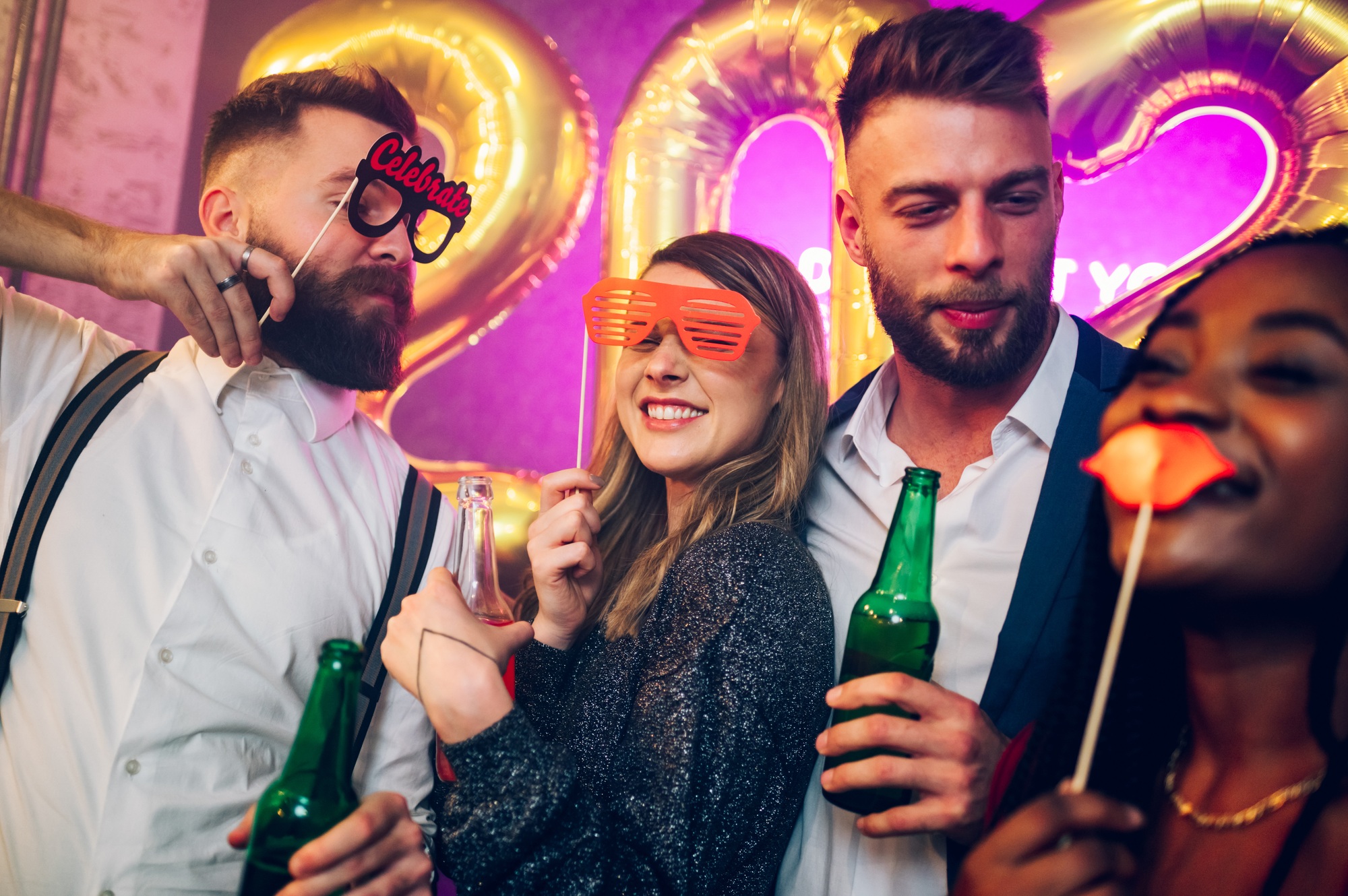 Multiracial friends celebrating new years eve with party props and drinks in the club