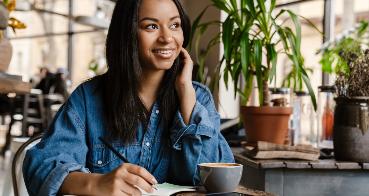 Smiling young african woman writing in notebook