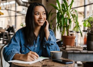 Smiling young african woman writing in notebook