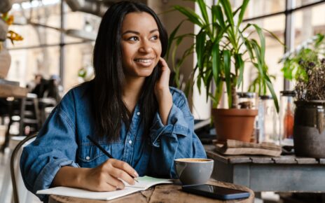 Smiling young african woman writing in notebook