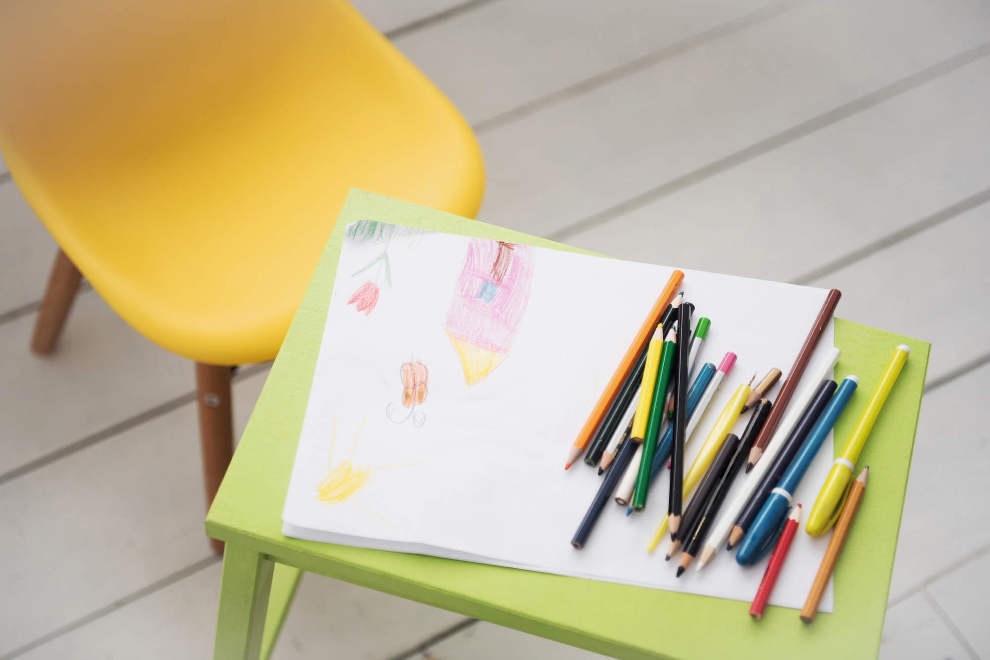 A frame with a kid drowing and colored pencils