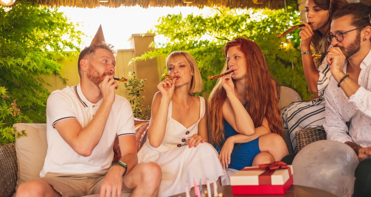 Friends blowing party whistles at birthday party
