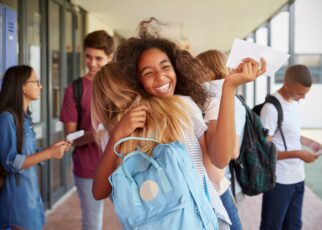 Two girls celebrating exam results in school corridor